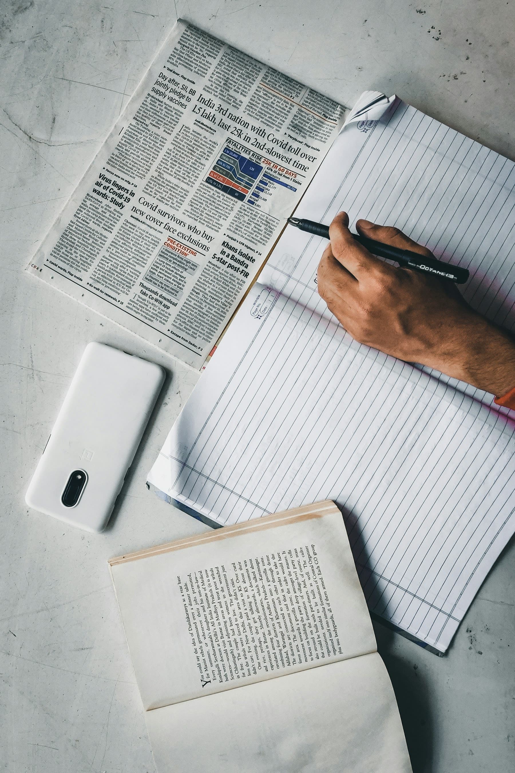 A newspaper, open book, and notebook prepared for study