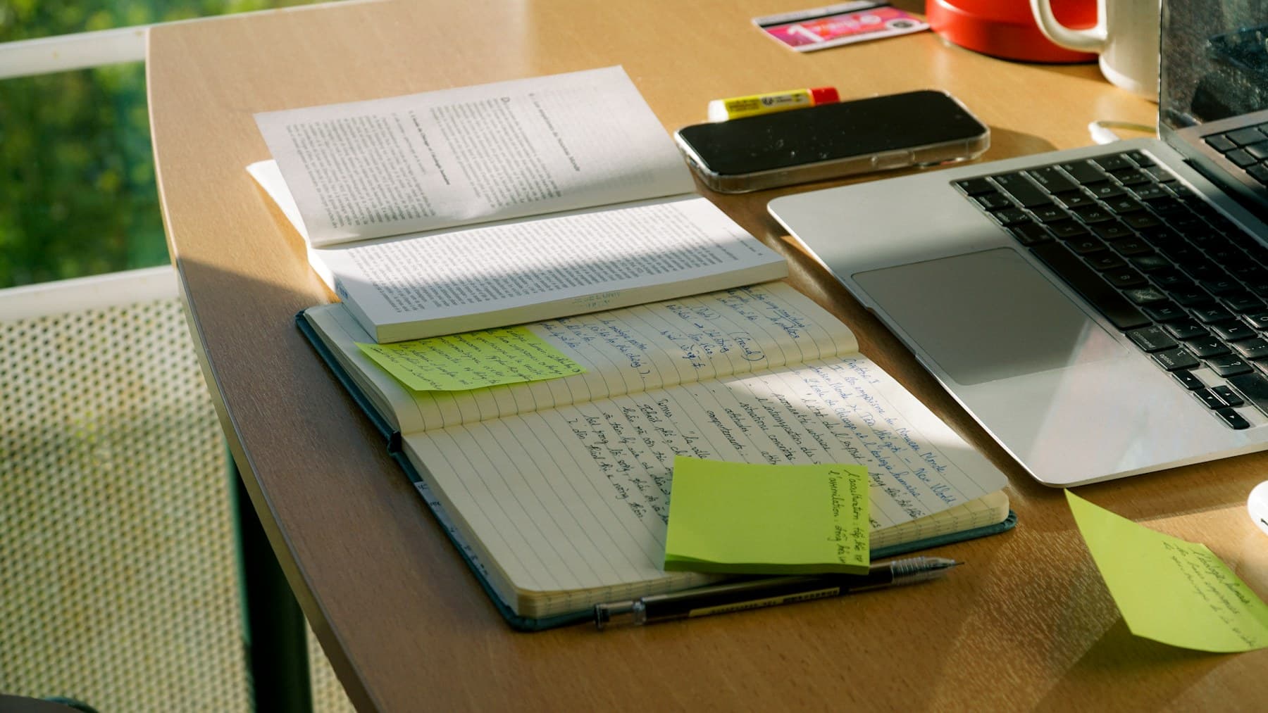 An active study desk with handwritten notes, a book, and a laptop